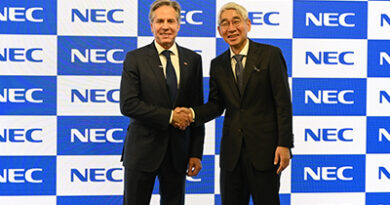 US Foreign Secretary Blinken poses for a photo with NEC President and CEO Takayuki Morita in front of a wall of blue and white NEC logos to promote Open RAN